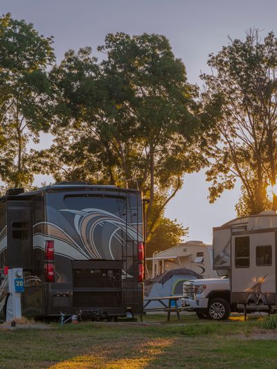 A bunch of RVs parked for camping at a resort at sunset.