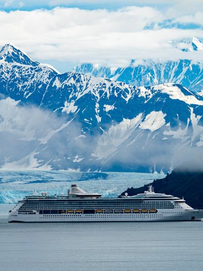 A cruise ship in Alaska passing glaciers and snow-capped mountains.