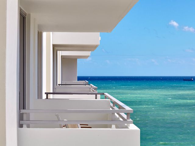A row of white hotel balconies surrounded by a turquoise ocean.