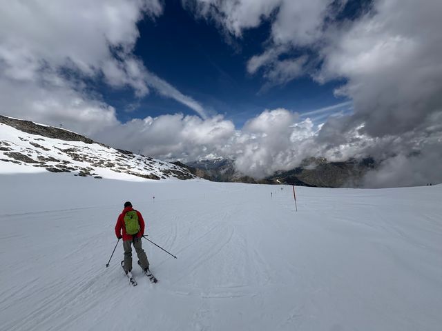 A man skiiing on Hintertux Glacier down a snowy run surrounded by clouds.