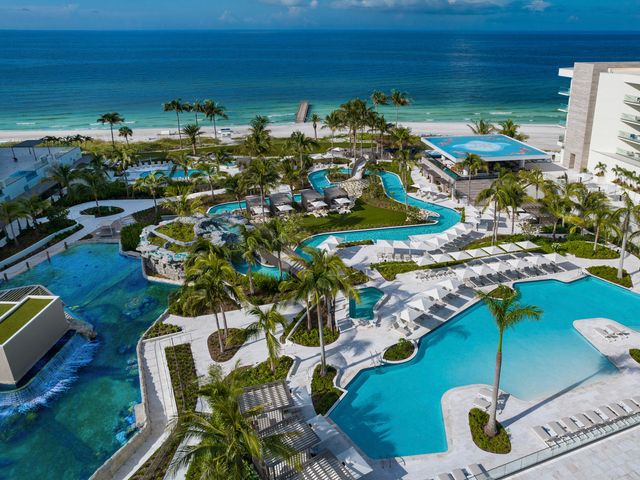 A view of a hotel pool and lazy river facing a tropical beach.