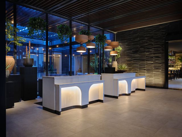 A fluted white check-in desk with dim lighting at Kimpton Santo San Antonio-Riverwalk.
