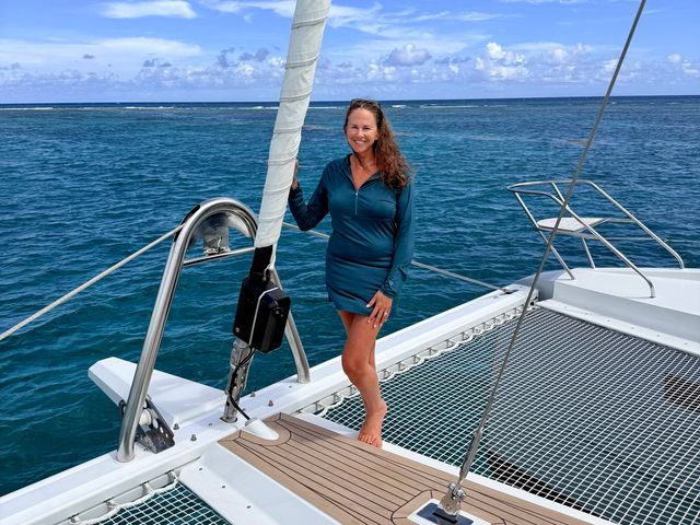 A woman wearing a turquoise dress on a catamaran yacht.