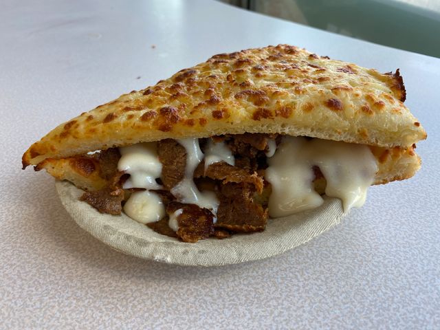 A pita stuffed with slices of meat covered with melted cheese.