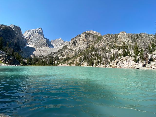 A turquoise green lake next to mountains at Grand Tetons.