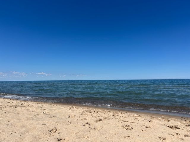 Waves breaking along the beach at Indiana Dunes National Park with the Chicago skyline barely visible in the horizon line.