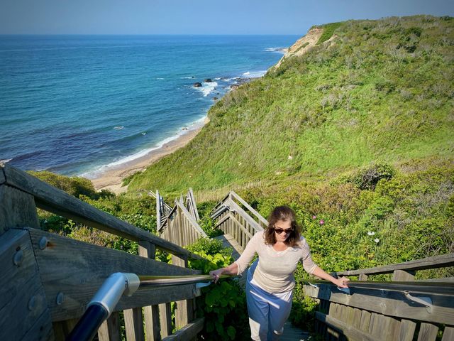 A woman is seen climbing up a steep wooden staircase from a pretty beach.