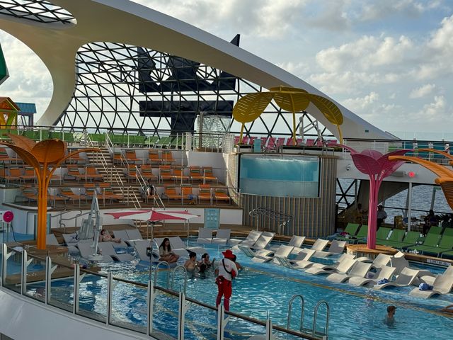 A cruise ship pool with stadium seating and a lifeguard watching over the action.