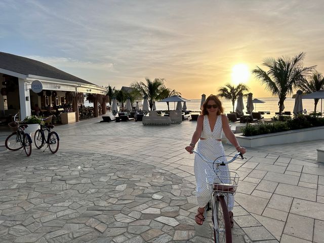A woman is seen smiling at the camera while on a bike at a Sandals Resort.
