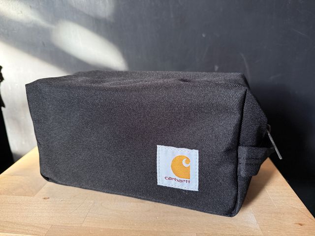 A Carhartt Travel Kit bag sitting on a wood table in sunlight.