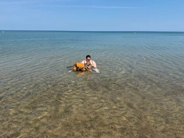 A women embraces her dog while swimming in the water at Indiana Dunes National Park.