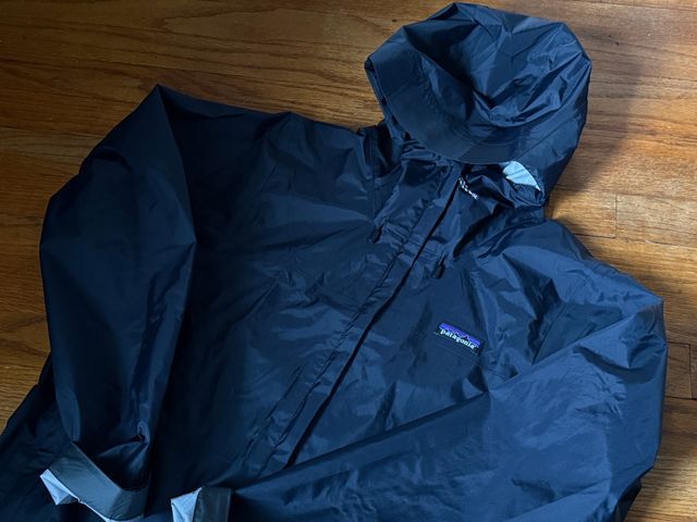 A blue Patagonia Torrentshell 3L Rain Jacket on a wood floor.
