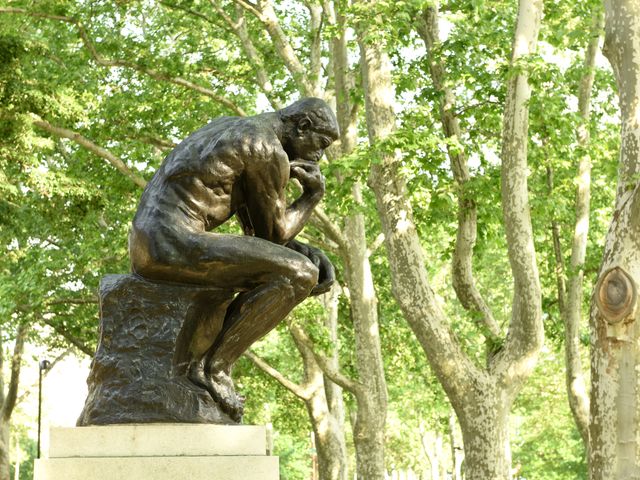 A sculpture of a man sitting and thinking surrounded by trees at the Rodin Museum in Philadelphia.