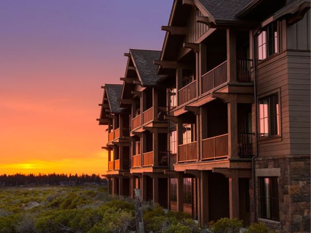 A rustic looking lodge building with balconies at sunset.