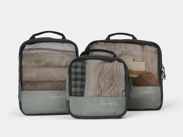 Three packing cubes, each a different size, with mesh and a label reading "Nomatic," against a white background.