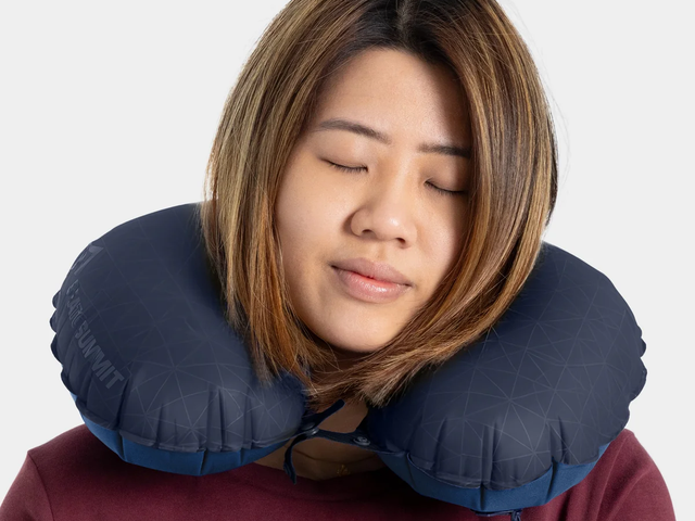 A woman sleeps while wearing a U-shaped inflatable neck pillow.