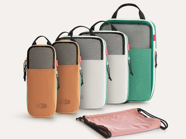 Five packing cubes and a drawstring pouch in different bright colors against a white background.
