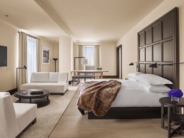 A suite at the New York Edition with a large bed, couches, table, and upscale decor.