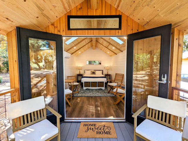 A glamping cabin with a porch, a bed, and chairs at Wildhaven Sonoma.