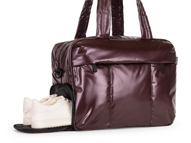 A Calpak Luka Duffel with white shoes half placed into a bottom shoe pouch.