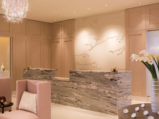 The spa reception at Four Seasons Resort Orlando at Walt Disney World Resort with a marble check-in desk, pink chairs, flowers, and a chandelier.