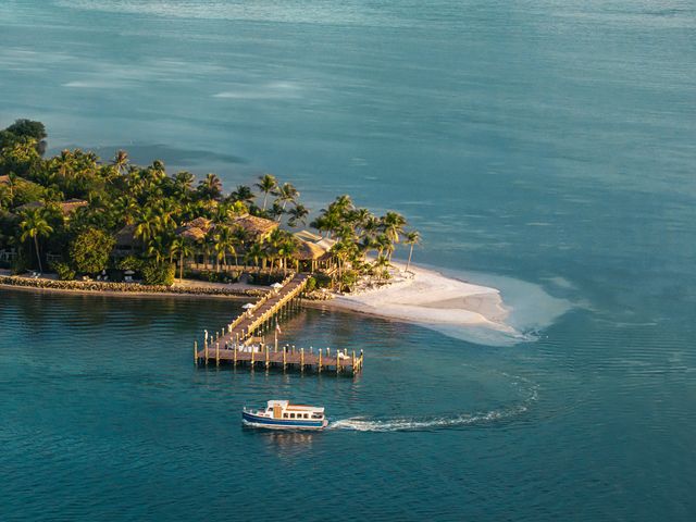 A tropical island with a small beach, a dock, and a boat.