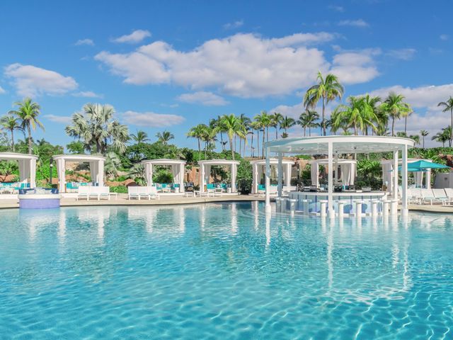 The in-pool Coral Bar at Atlantis Paradise Island with a circular bar with stools in the pool surrounded by cabanas on the side.