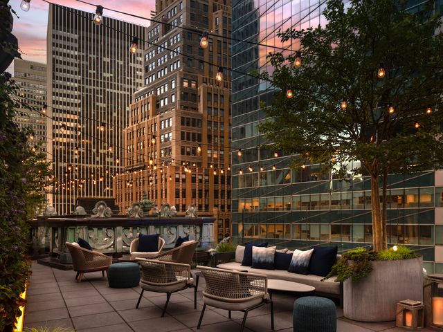 A rooftop with NYC skyscrapers visible at a rooftop bar at The Knickerbocker Hotel.
