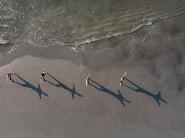 An overhead drone shot of four people doing yoga on the beach at Hilton Head Health Wellness Resort & Spa.