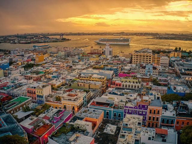 Aerial view of San Juan, Puerto Rico at sunset with a cruise ship in the distance.