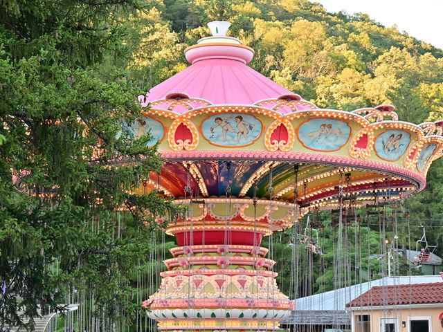 A pink, orange, and blue swing ride with green hills in the background