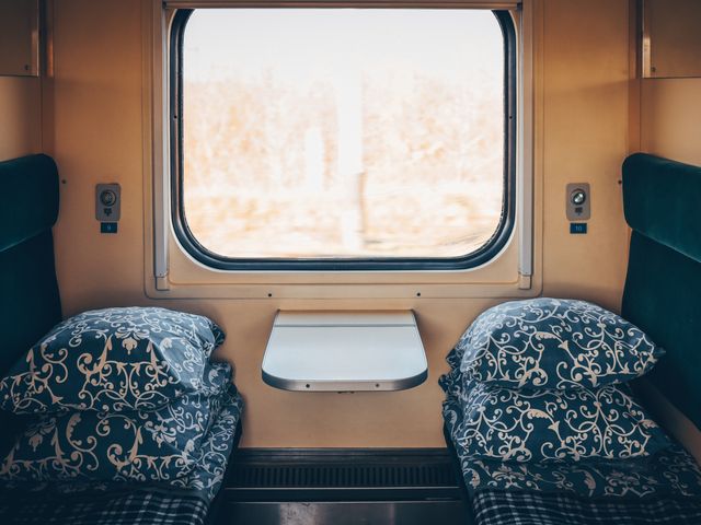 Interior of a coupe in a passenger train car with stacked pillows next to the window.