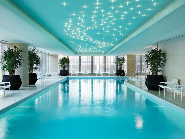 An indoor pool at the Chuan Spa at The Langham, Chicago with white chairs on the side and a blue ceiling covered with stars.