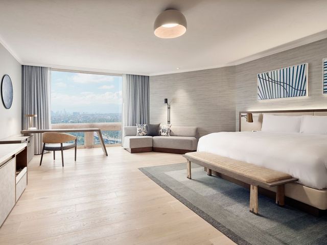 A hotel room with a bed, bench, desk, chair, and couch at JW Marriott Hotel Mexico City Polanco.