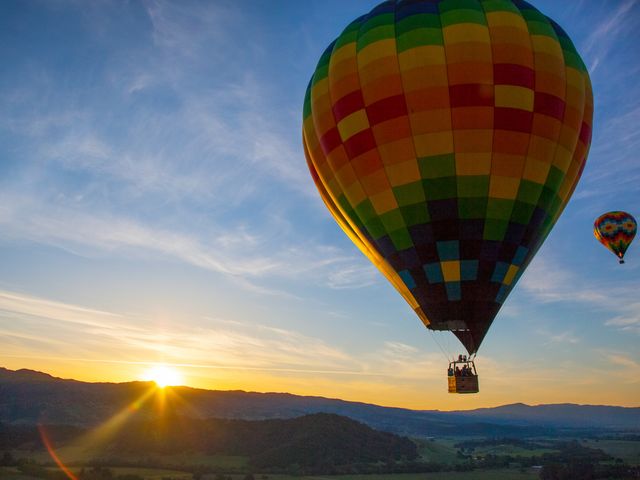Colorful hot air balloons float over a sunrise in Napa Valley.