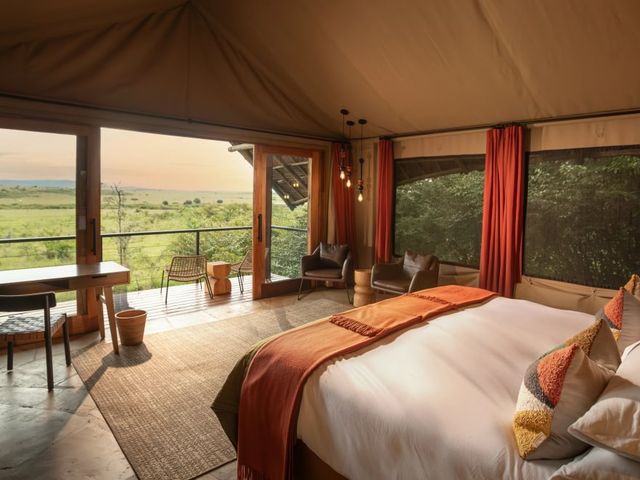 Luxury canvas safari hotel room looks out over the landscape from open patio doors.