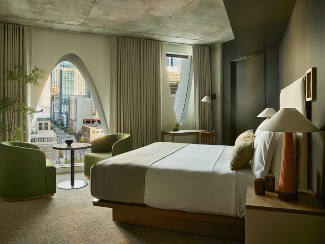 A King room at Populus Denver with views of the city through arched windows.