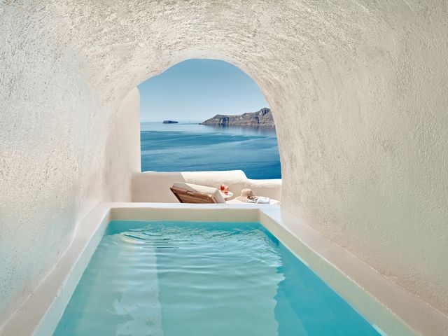 A blue pool inside a white cave looking out at the ocean at Mystique in Santorini.