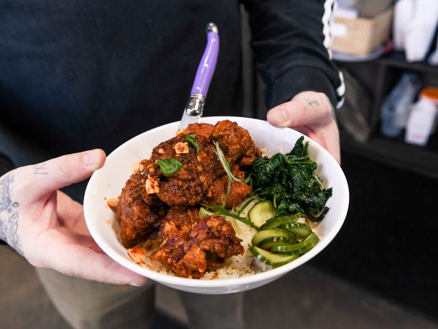Hands serving a plated meal at Eem in Portland.
