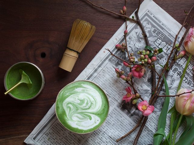 A matcha latte seen overhead on top of newspaper and flowers from Smith Tea in Portland.