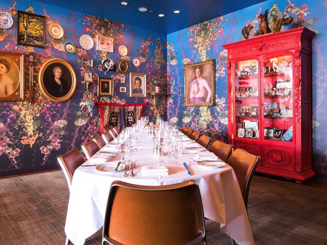 A room at 21c Museum Hotel Louisville with bold print wallpaper, framed art, a red hutch, and a set dining table.