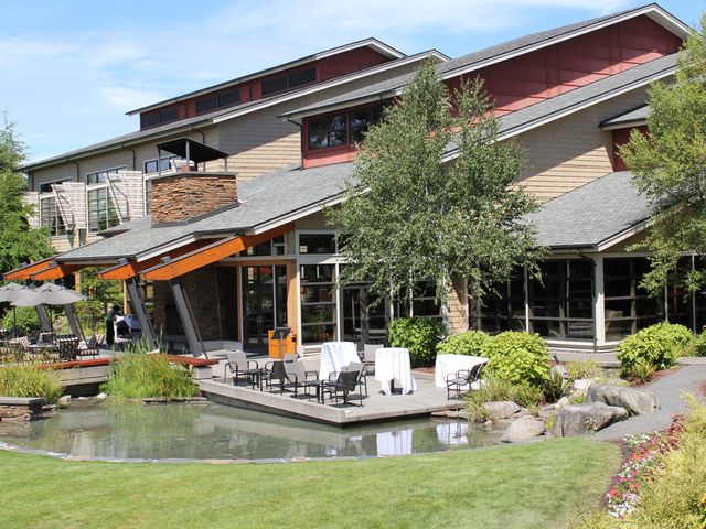 A modern looking building with balconies and an outdoor seating area next to a small pond.