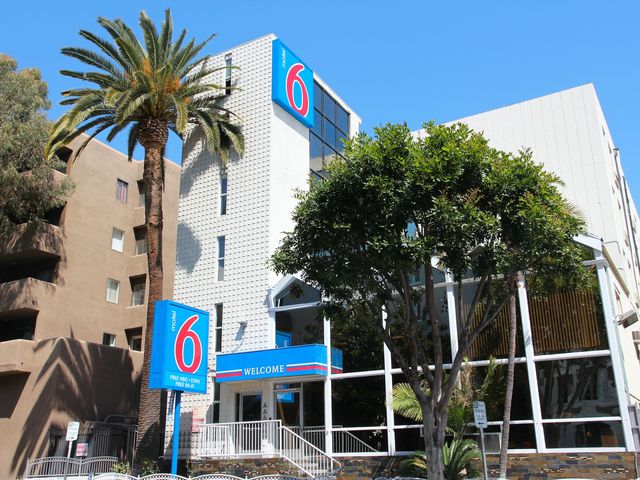 The exterior view of a Motel 6 hotel with trees on the outside.
