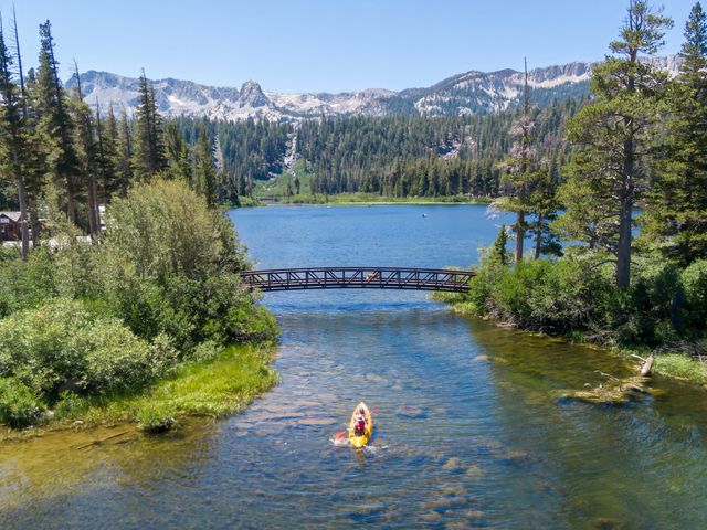 Aerial view of two people kayaking on Twin Lakes, Mammoth Lakes in California surrounded by pine trees and mountain views.