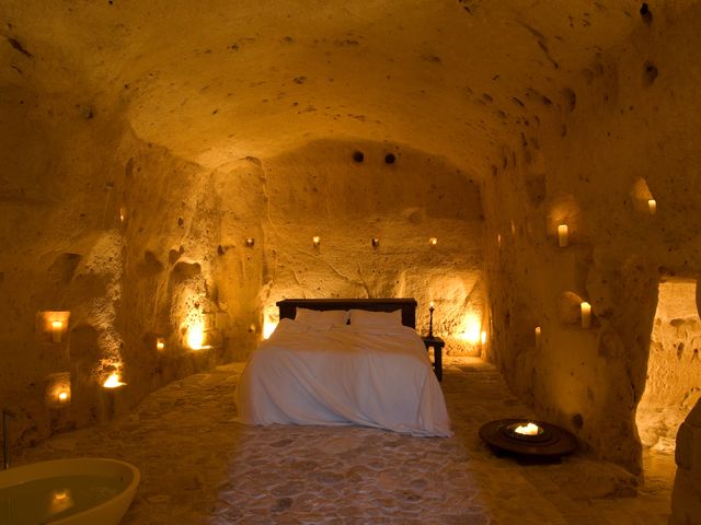 Inside a cave room at Sextantio Le Grotte Della Civita with a bed and candlelight all over the walls