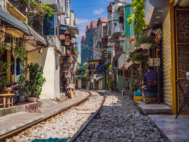 Colorful street view of Hanoi, Vietnam, with a train track running down the road.