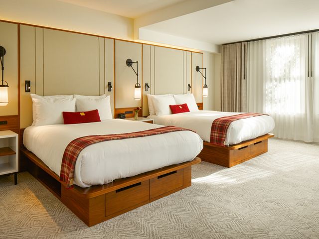 A hotel room at Limelight Aspen with two beds and red, plaid, and wood accents.