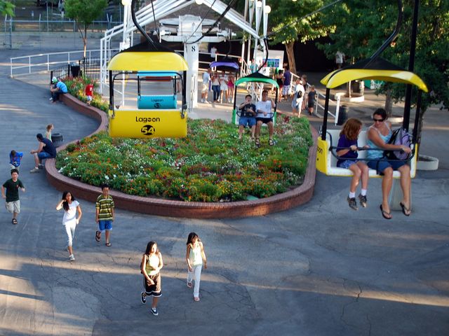 An aerial view of amusement park goers and riders on a yellow sky-glider attraction