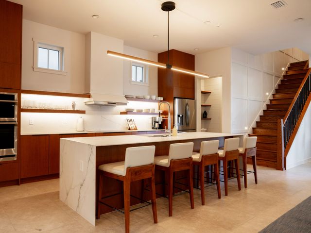 An upscale kitchen with a counter lined with seats inside a room at The Evermore Residences at Evermore Orlando Resort.