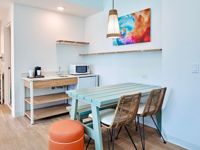 A dining area inside a room at Universal Endless Summer Resort Surfside Inn and Suites with two chairs and a turquoise wood table.